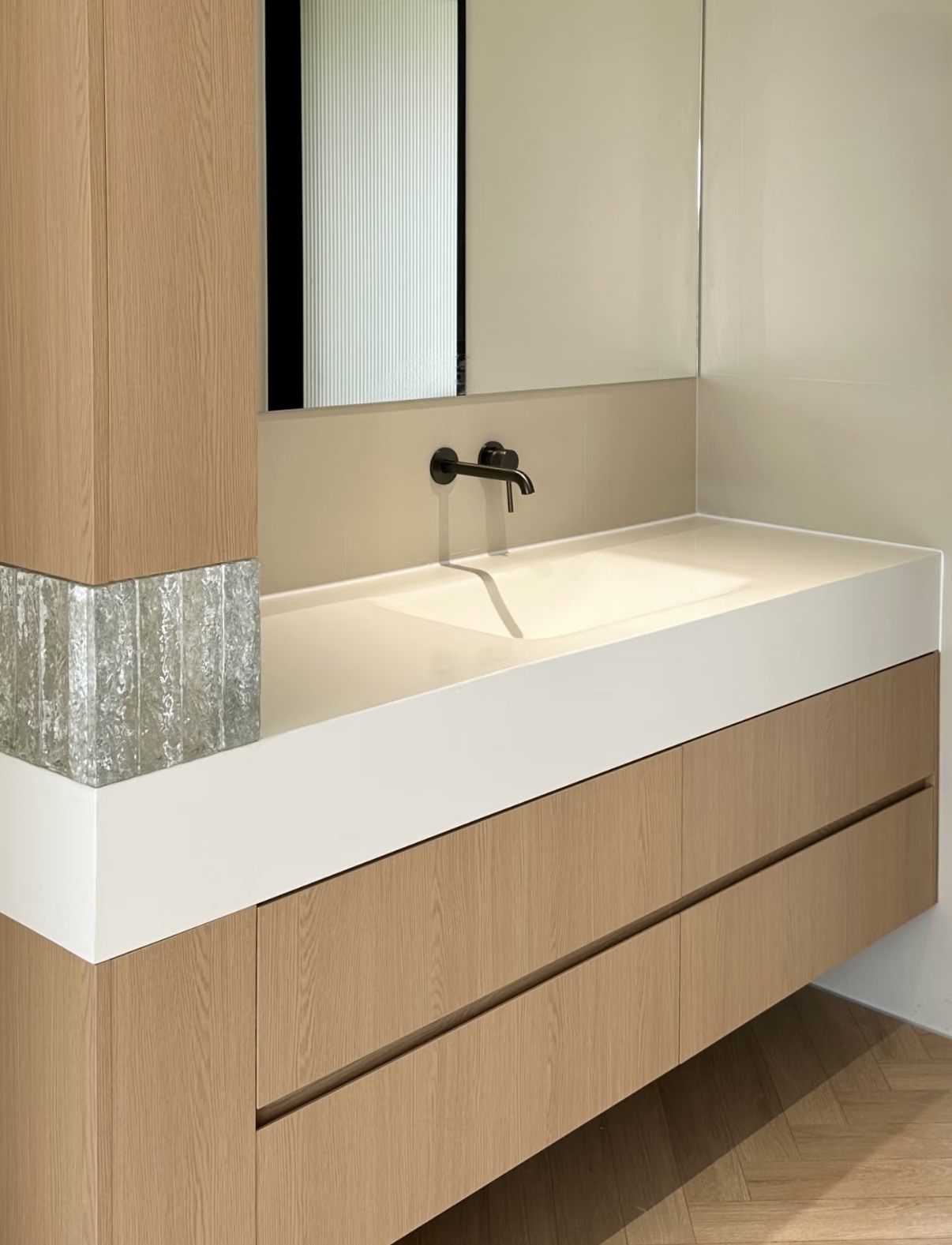 Lave custom oak vanity with integrated sintered stone basin, full-height oak column and herringbone floor — Minimal Japandi installation