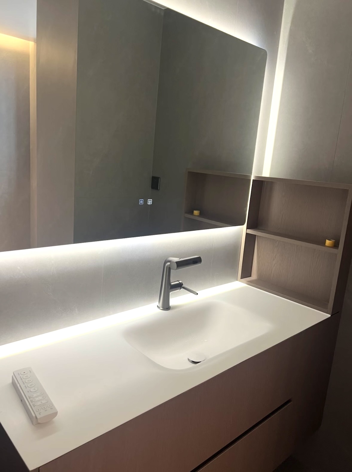 Floating wood-grain vanity with integrated sink and illuminated mirror in a Brighton bathroom